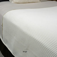Bed made with beige waffle supreme coverlet.