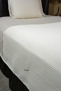 Bed made with beige waffle supreme coverlet.